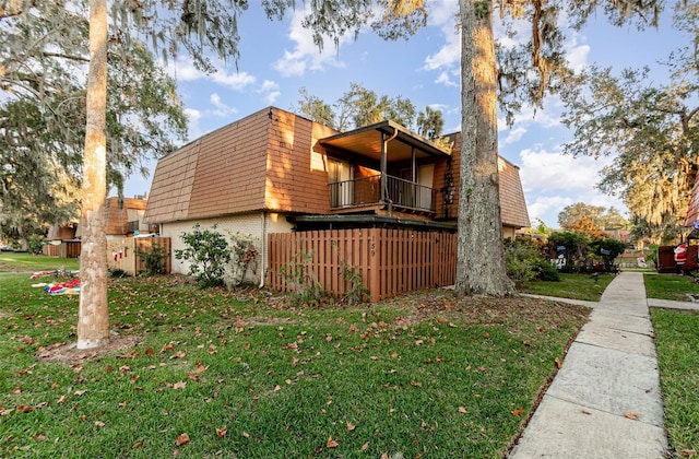 view of side of home featuring a balcony and a yard