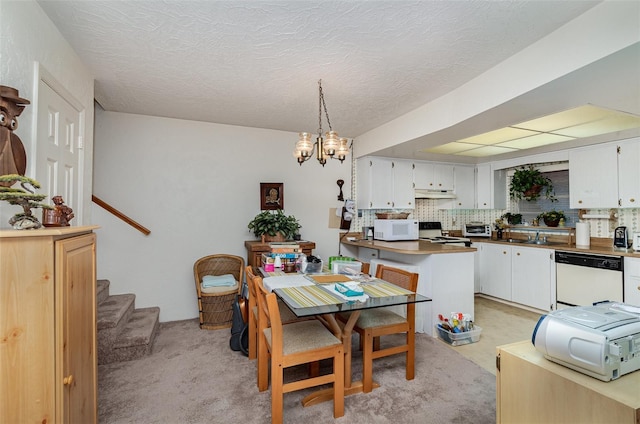 dining space with light carpet, a textured ceiling, a notable chandelier, and sink