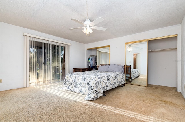 carpeted bedroom featuring a textured ceiling, ceiling fan, and two closets