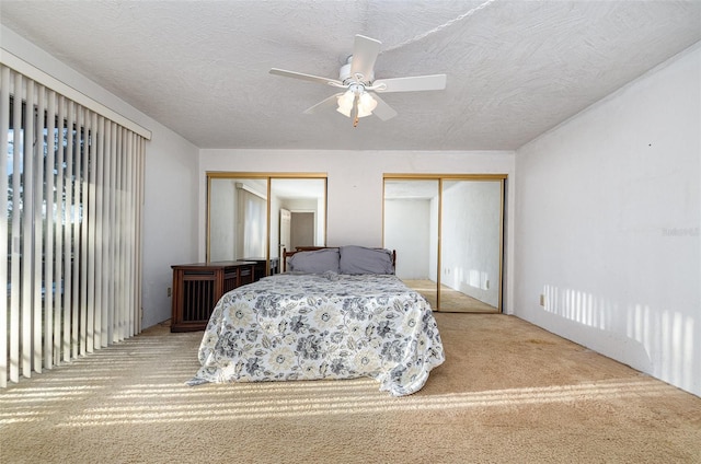 bedroom featuring ceiling fan, light carpet, and two closets