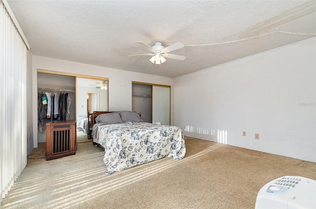 carpeted bedroom featuring a textured ceiling, ceiling fan, and two closets