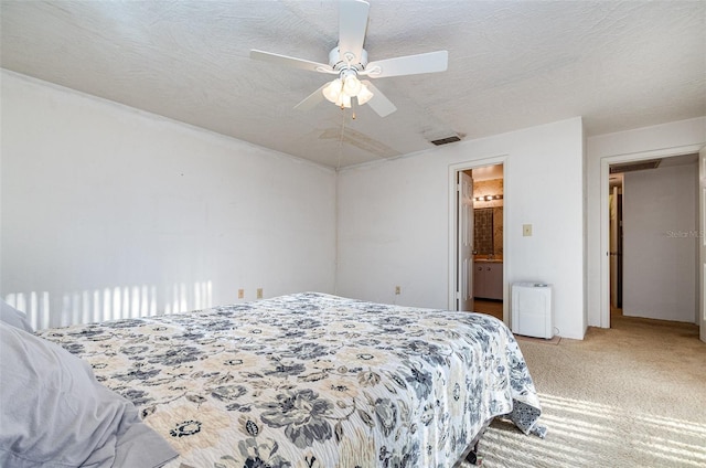 bedroom with a textured ceiling, connected bathroom, light colored carpet, and ceiling fan