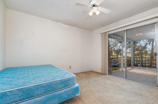 carpeted bedroom with access to outside, ceiling fan, and a textured ceiling