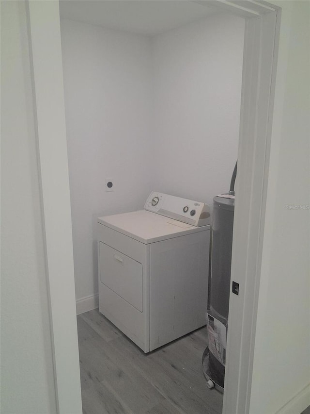 laundry room featuring washer / dryer, light hardwood / wood-style flooring, and water heater