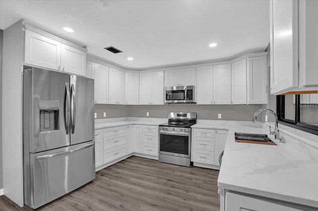 kitchen with light stone counters, sink, white cabinetry, and stainless steel appliances