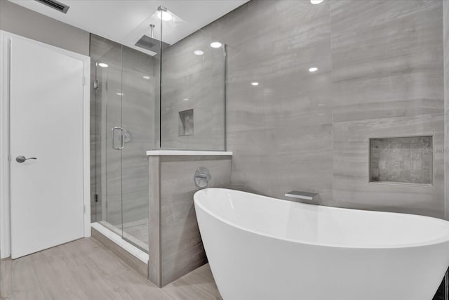 bathroom featuring tile walls and independent shower and bath