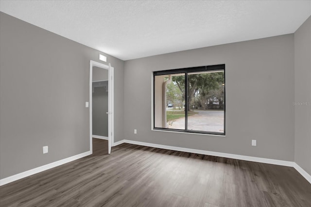 spare room with dark hardwood / wood-style floors and a textured ceiling