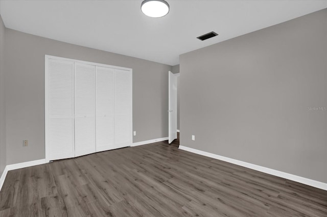 unfurnished bedroom featuring a closet and dark hardwood / wood-style flooring