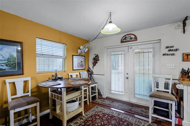 dining room with a textured ceiling, dark wood-type flooring, and french doors