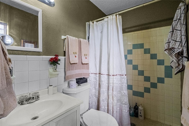 bathroom featuring vanity, a textured ceiling, toilet, and tile walls