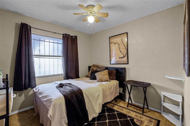 bedroom featuring dark colored carpet, a textured ceiling, and ceiling fan