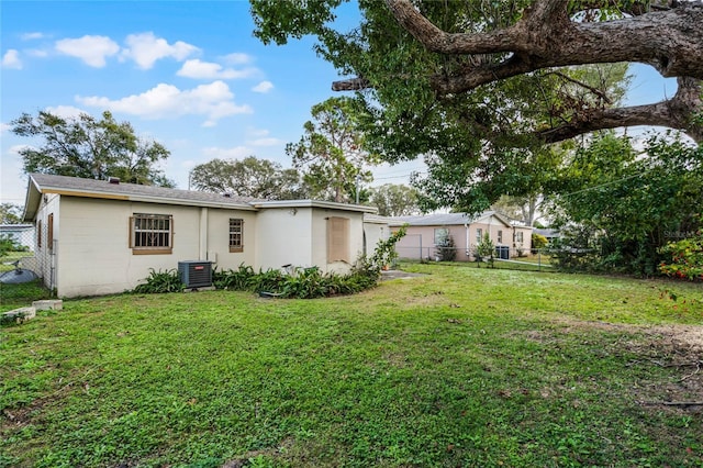 rear view of property featuring a lawn and central air condition unit