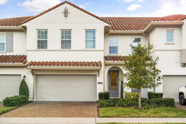 view of front of home with a garage, decorative driveway, a tile roof, and stucco siding