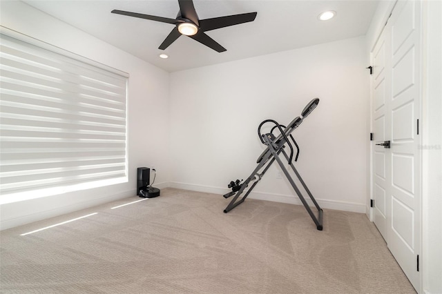 exercise area with ceiling fan and light colored carpet