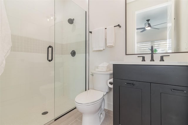 bathroom featuring ceiling fan, vanity, a shower with door, and toilet