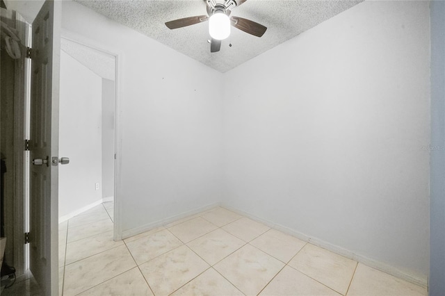 empty room featuring ceiling fan, light tile patterned floors, and a textured ceiling