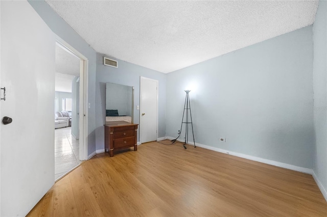 unfurnished bedroom with a textured ceiling and light wood-type flooring