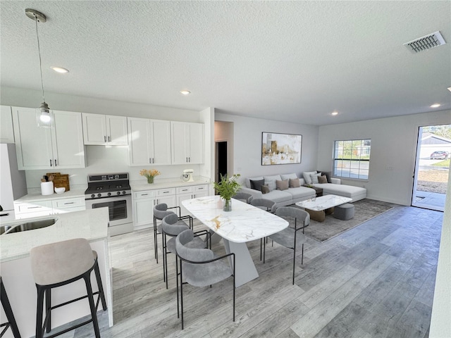 kitchen featuring stainless steel range, white cabinets, and light hardwood / wood-style floors