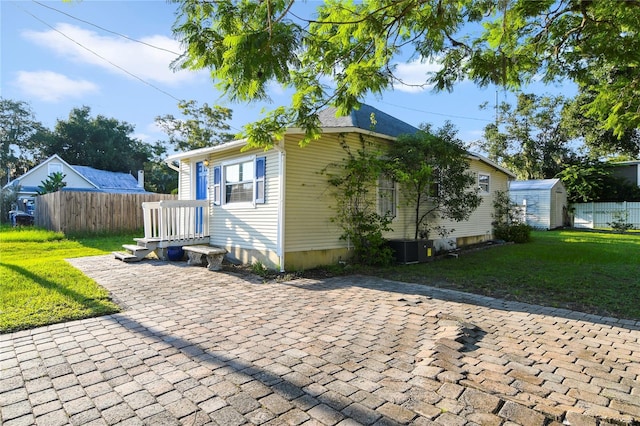 exterior space featuring cooling unit, a storage unit, and a lawn