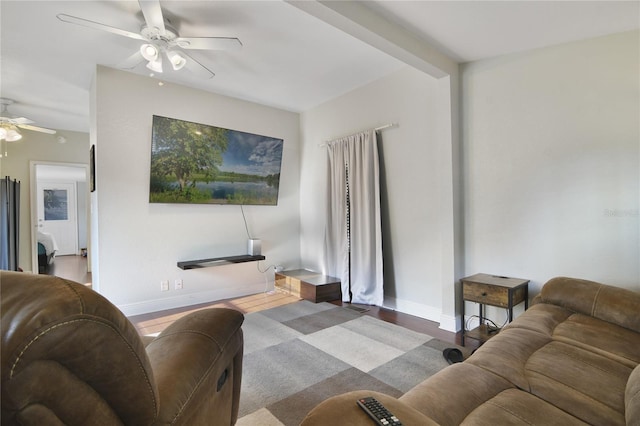 living room featuring beamed ceiling, dark hardwood / wood-style flooring, and ceiling fan