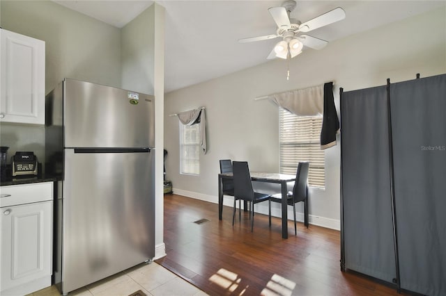 kitchen with white cabinetry, ceiling fan, stainless steel fridge, and light hardwood / wood-style floors