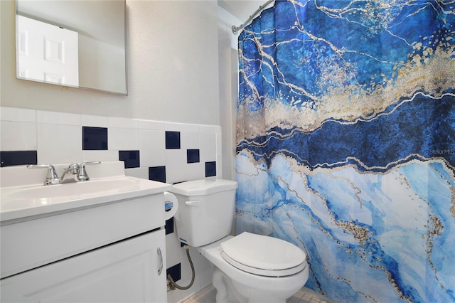 bathroom with vanity, toilet, and tile walls