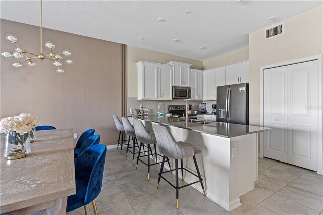 781 Ocean Course Ave Unit 601, Davenport, FL 33896 - kitchen with appliances with stainless steel finishes, a breakfast bar area, a peninsula, white cabinetry, and a chandelier