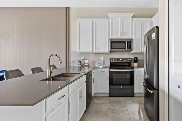 kitchen with white cabinets, sink, decorative backsplash, appliances with stainless steel finishes, and a kitchen bar