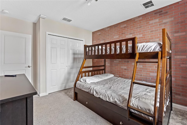 carpeted bedroom featuring a closet and brick wall