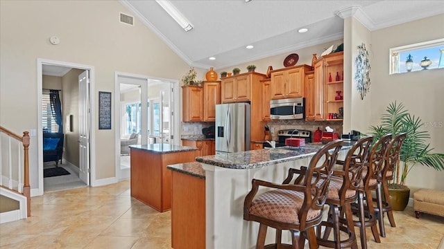 kitchen featuring appliances with stainless steel finishes, a kitchen island, ornamental molding, and a healthy amount of sunlight