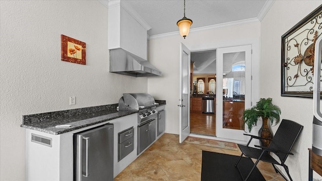 kitchen with dark stone counters, crown molding, decorative light fixtures, white cabinetry, and stainless steel refrigerator