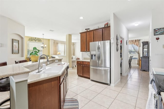 kitchen featuring a kitchen bar, stainless steel appliances, sink, decorative light fixtures, and an island with sink