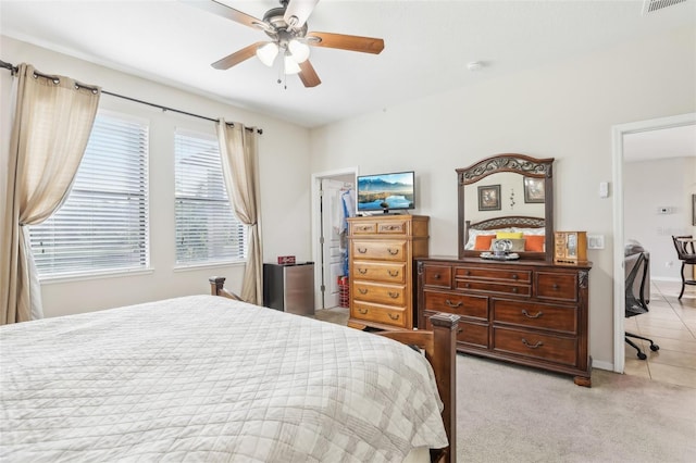 bedroom featuring light carpet, a walk in closet, a closet, and ceiling fan