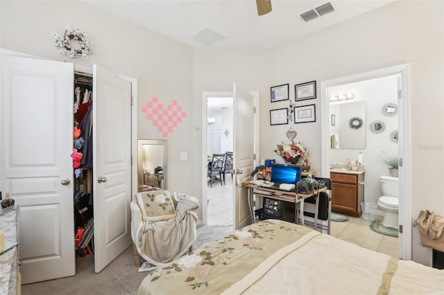 tiled bedroom featuring a closet, ensuite bath, and ceiling fan