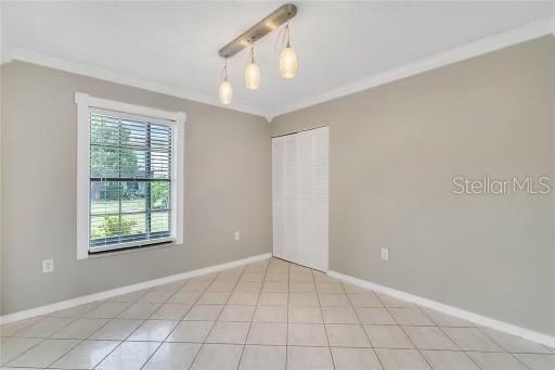 empty room with light tile patterned floors and ornamental molding