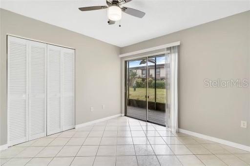 unfurnished bedroom featuring ceiling fan, light tile patterned floors, access to outside, and a closet