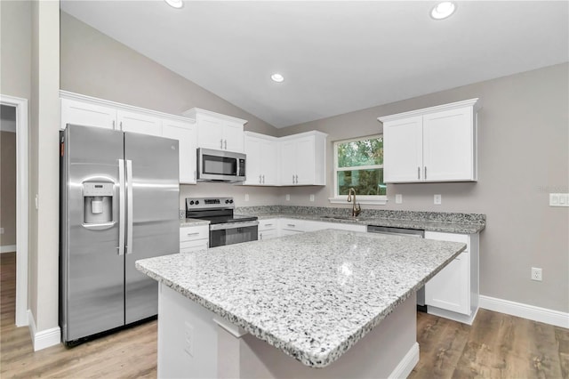 kitchen featuring vaulted ceiling, a kitchen island, sink, white cabinetry, and stainless steel appliances