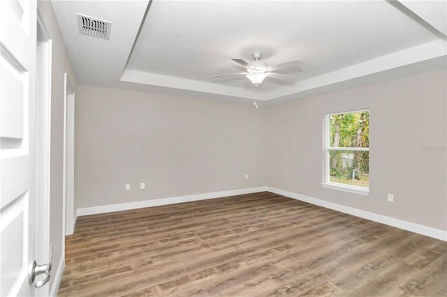 unfurnished bedroom featuring ceiling fan, wood-type flooring, and a raised ceiling