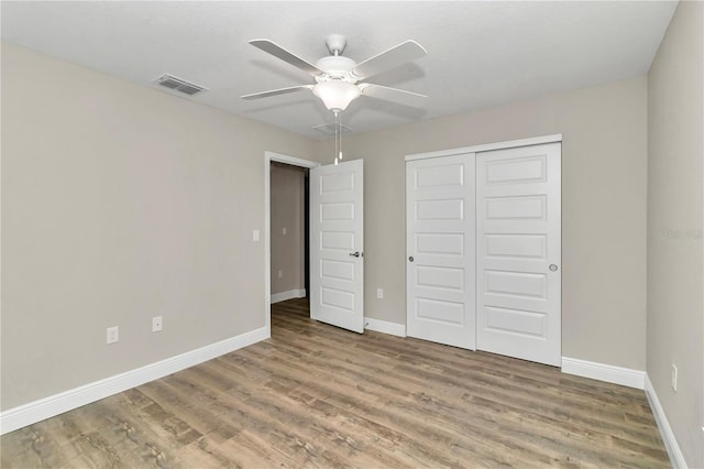 unfurnished bedroom featuring ceiling fan, hardwood / wood-style flooring, and a closet