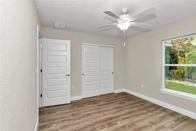 unfurnished bedroom featuring ceiling fan, a closet, and wood-type flooring