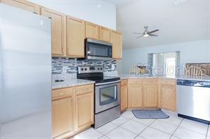 kitchen featuring tasteful backsplash, stainless steel appliances, ceiling fan, light brown cabinets, and light tile patterned flooring