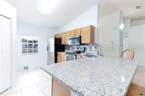 kitchen featuring sink, appliances with stainless steel finishes, tasteful backsplash, light stone counters, and kitchen peninsula