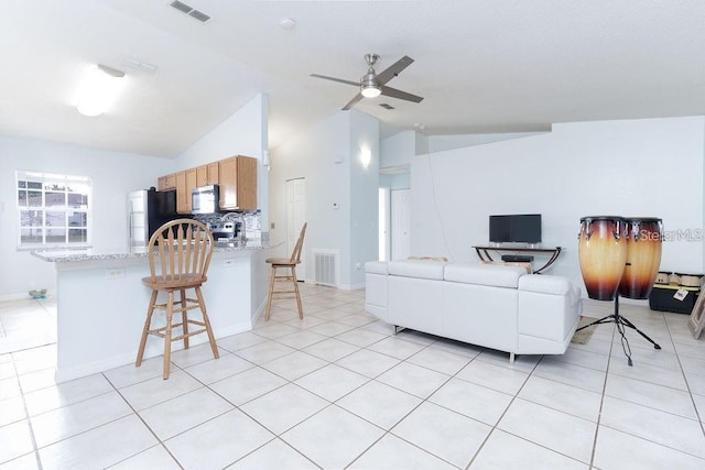 tiled living room featuring ceiling fan and vaulted ceiling