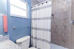 bathroom featuring vanity, curtained shower, and toilet