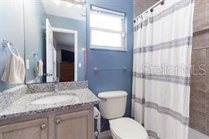 bathroom featuring a shower with shower curtain, vanity, and toilet