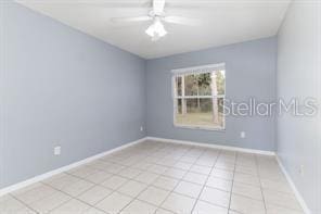 tiled spare room featuring ceiling fan