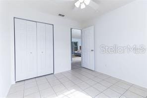 unfurnished bedroom with ceiling fan, a closet, and light tile patterned floors