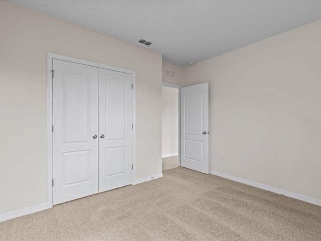 unfurnished bedroom featuring light colored carpet and a closet