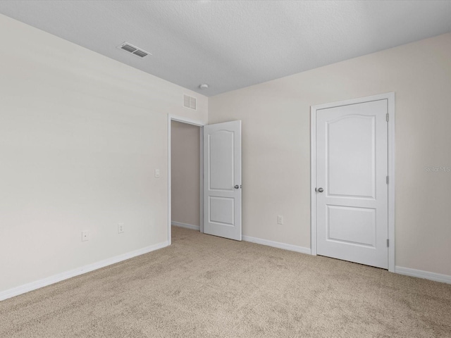 empty room featuring light colored carpet and a textured ceiling