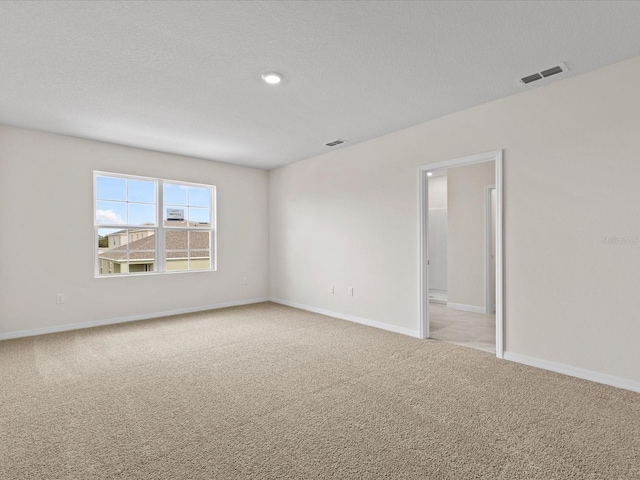 empty room featuring a textured ceiling and light colored carpet